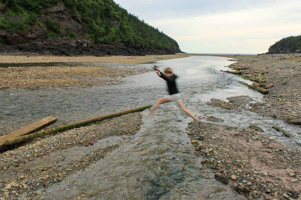 Jumping a channel of Point Wolfe River at Point Wolfe Beach in Fundy Nationl Park